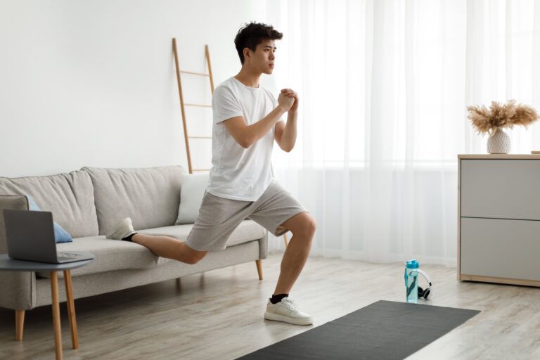 A young asian male is wearing light brown shorts and white T shirt while doing a squat action with his leg on the lounge. Hip Pain Five Dock.