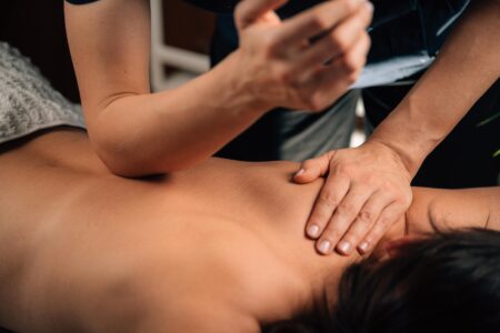 A male patient lying on a table being treated with massage. The person is using their elbow. Chiropractic with massage for back pain. Back Pain Croydon Park