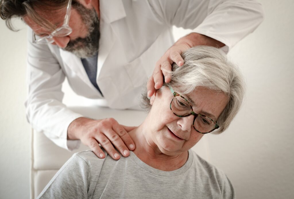 Older women getting treatment from chiropractor for neck arthritis and neck pain. Doctor is stretching patients neck to the left.