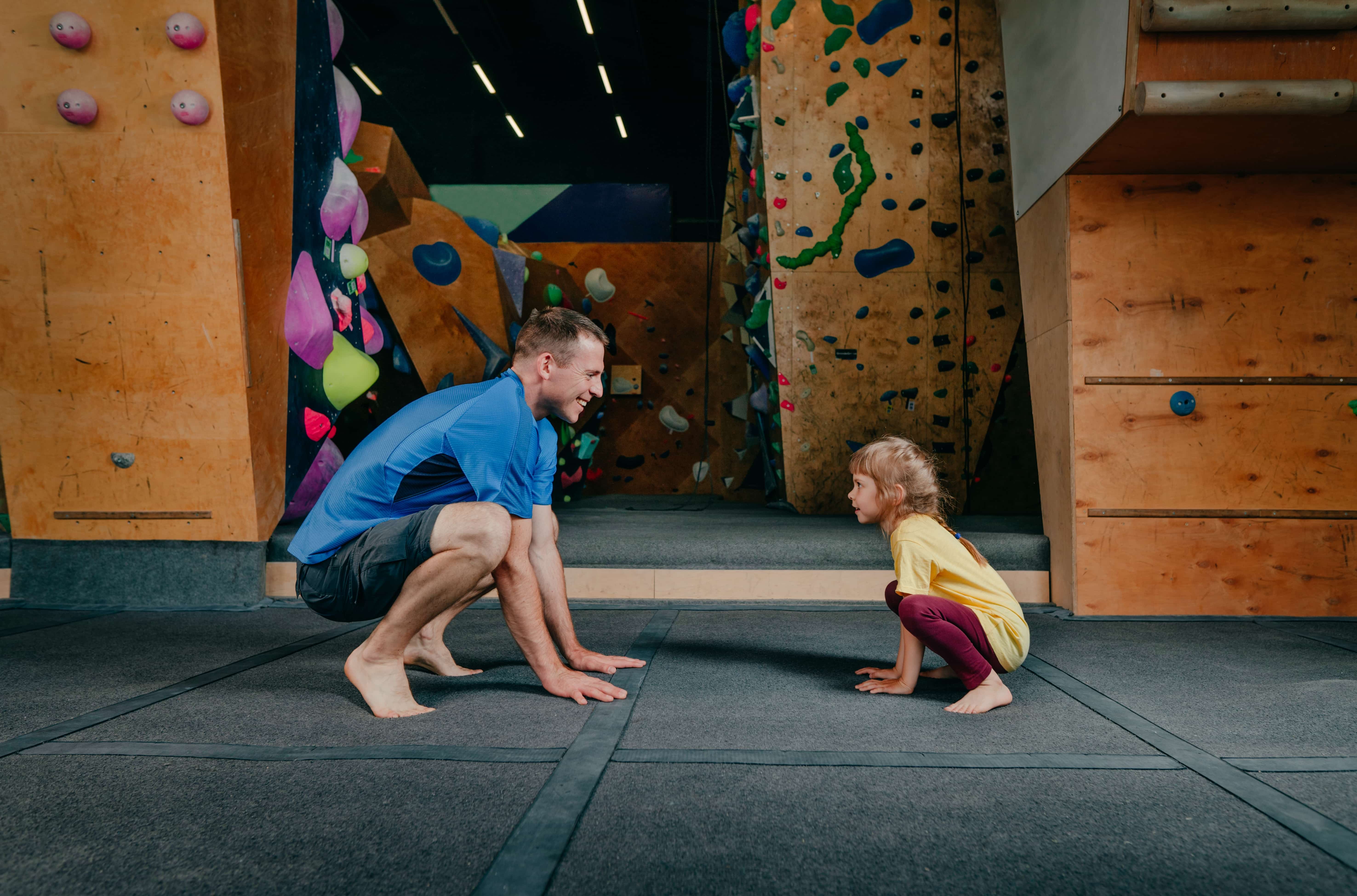 Fun exercises as part of rehab. Father and daughter doing squats in rock climbing gym
