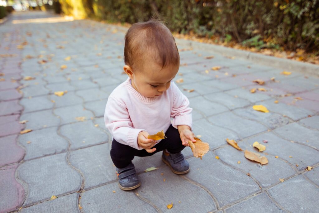 toddler squat sitting-picking up leafs