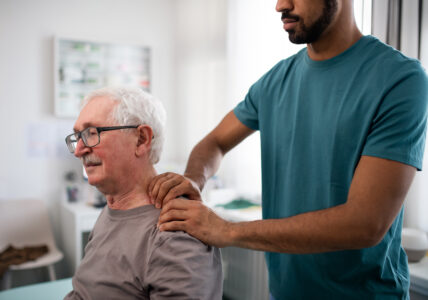 Elderly patient having massage on shoulder with chiropractic for treatment of injury and shoulder pain. Osteopathic care and chiropractic care.