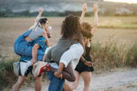 Group of young people running in a field. Hands up in the air with happiness