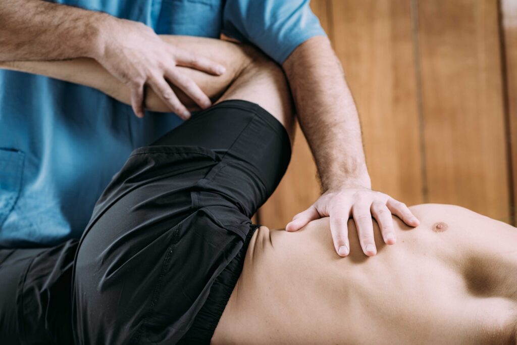 person lying on back. left hip bent up to test hip cartilage. chiropractor bending knee across body testing for hip pain.