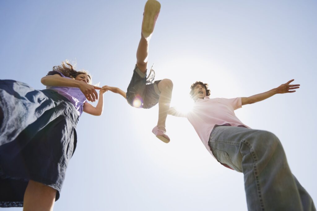 Family with parents on either side of a child. Lifting the child into the air a swing them forward,