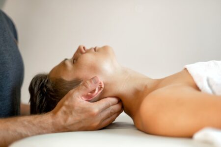 A lady on a treatment table having neck traction. Traction is performed by doctor with hands under the neck gently pulling on the neck. Traction helps calm the nervous system. Osteopath treatment.