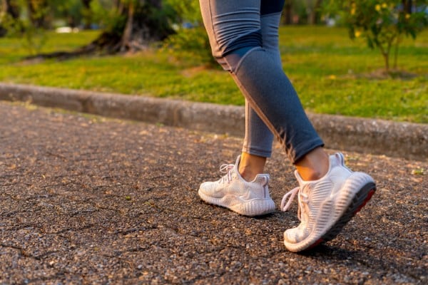 Young woman walking exercise on a brown street with white shoes