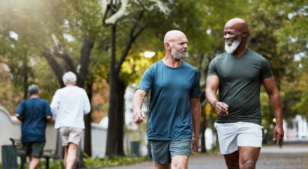 men walking together at community park while talking and doing cardio training outdoor in nature. preventive care - walking.