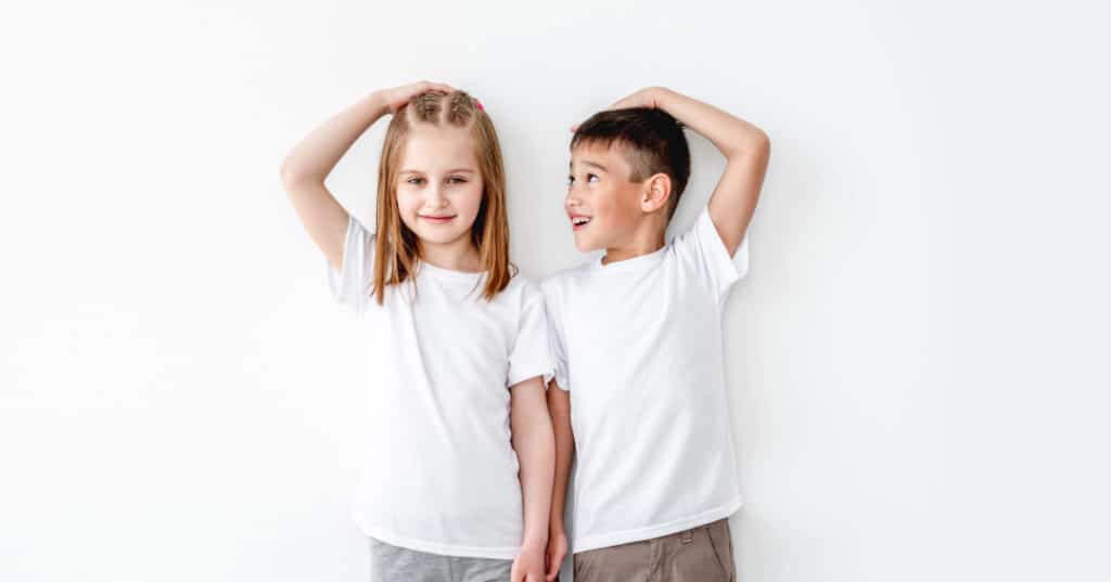 Two kids standing next to each other wearing white T shirts.