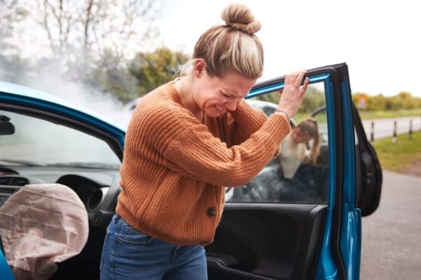 Female Motorist suffering from whiplash following a car crash. Getting Out Of Car