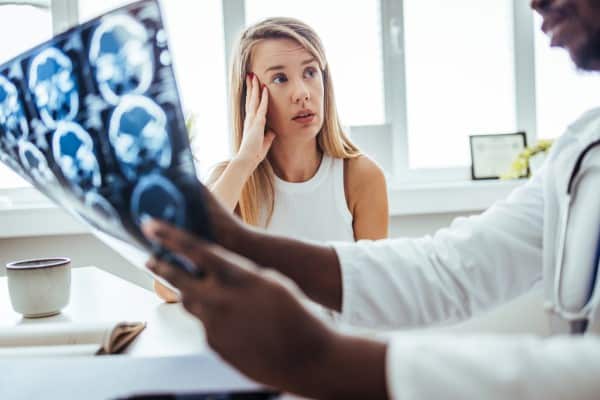 Doctor holding x-ray radiography film explain the result to patient. medical doctor diagnosing patient with cervicogenic headaches seeing Magnetic Resonance Imaging. Neck pain and headaches are diagnosed with MRI.