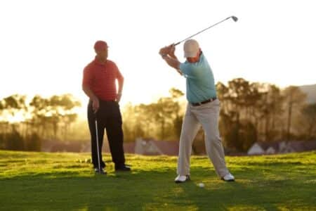 Two older male golfers going through a round of golf. Haelthy aging shown by happy people outdoors playing golf.