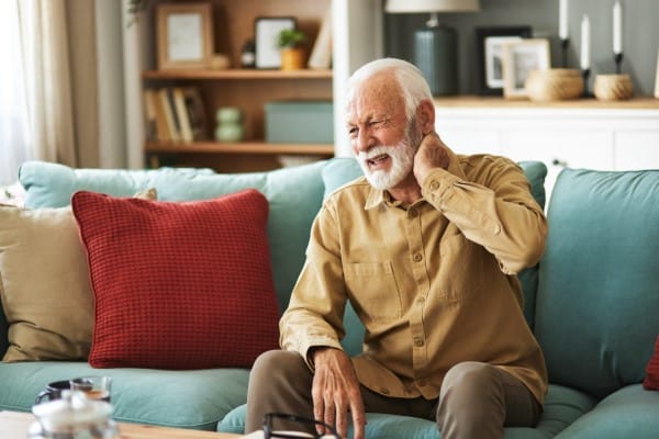 older man holding is neck due to stiffness and pain caused by arthritis in his neck.