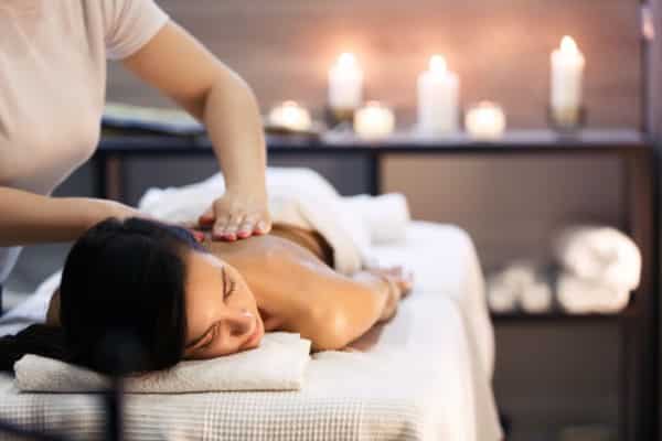 woman laying face down on massage table. Getting a lower back massage to help promote blood flow and relieve tension.