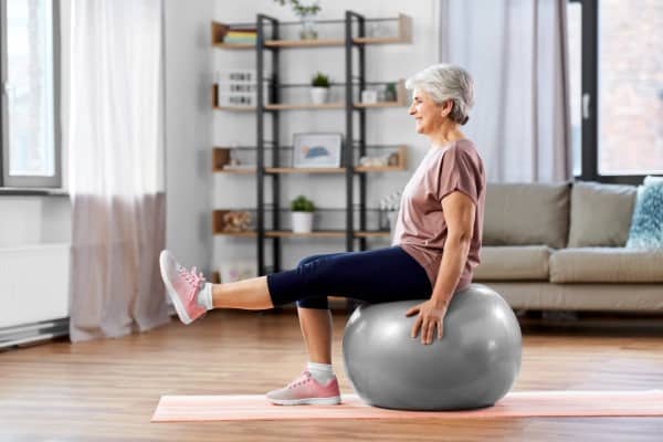 senior woman training with exercise ball to improve stability at home