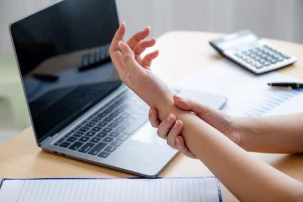 women suffering from wrist tendonitis from using her laptop.