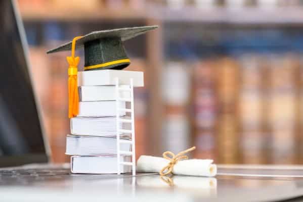 University Graduation cap ontop of a pile of textbooks.