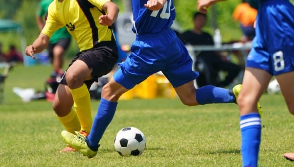 A soccer player dressed in blue taking a big kick.