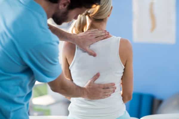 Male chiropractor giving back massage to female patient