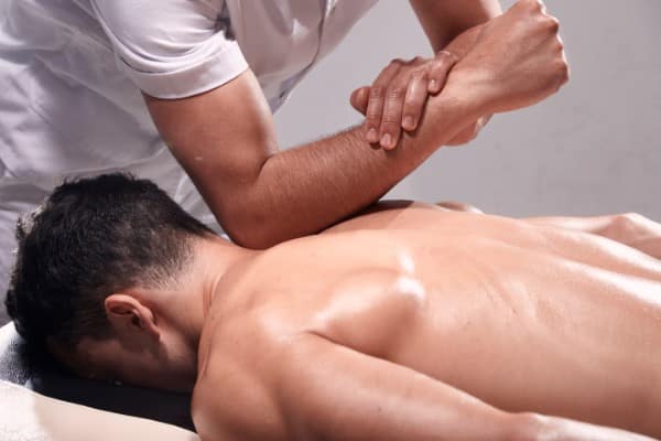 Male patient laying on the table being massaged on is lower back back by chiropractor