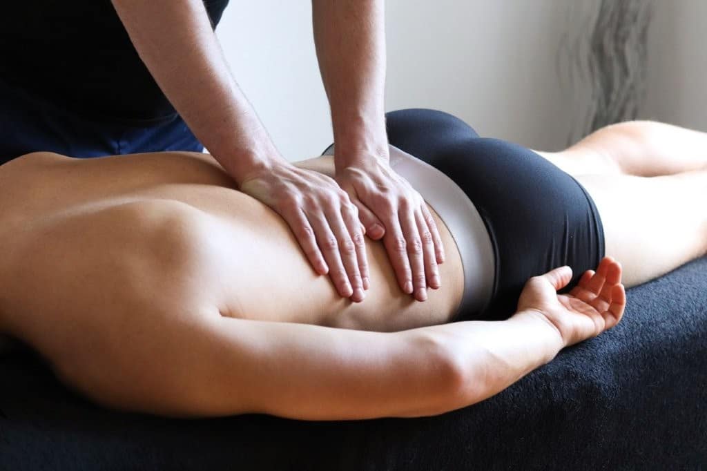 physical therapist places hands on patient lying on table, exposing back, relaxing muscles