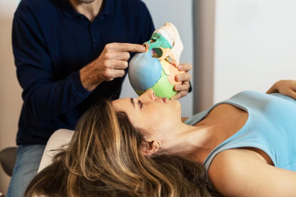 Chiropractor or osteopath Practitioner talking to patient about an educational demonstration of Cranial Anatomy