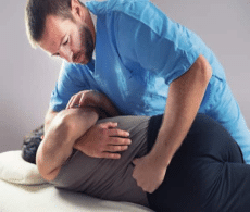 Chiropractor doing a lower back adjustment for a patient with lower back pain. The patient is lying on side and chiro is gently rolling them towards chiro. This stretch fascia, muscles and joints.