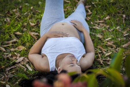 fertility five dock. Women's health represented by a pregnant lady lying on her back on grass. Sh eis wearing a white top. Chiropractic can help during pregnancy. Postpartum treatment in Five Dock.