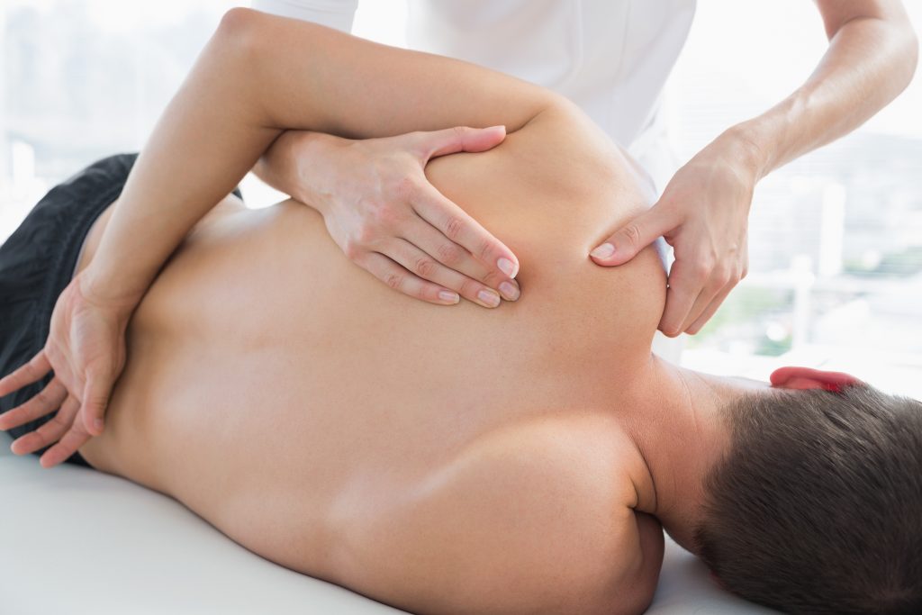 Physiotherapist massaging man with shoulder impingement