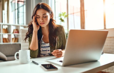 Desk slouch shown as lady sitting at desk holdign her temporal region. Chiro does chest stretches in the doorway to help.